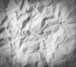 Crumpled up paper background representing wasted paper with traditional time clock systems.