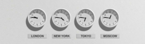White time clocks displaying time in four different regions mounted on white wall representing saving time with global workforce by using an online time clock system.