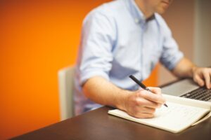 Remote employee working in home office writing.