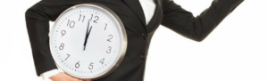Humorous girl in business suit running with big time clock tucked under her arm as her supervisor decides to consult Fingercheck on ways to address tardy employees.