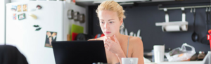 Young woman working from home in casual clothes looking at laptop.
