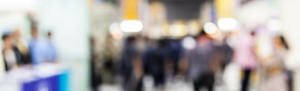 Trade show blurred, busy, signifying the need to prepare for trade show to stand out.