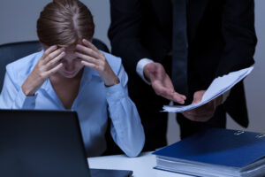 Stressed female employee being attacked by supervisor as a labor violation.