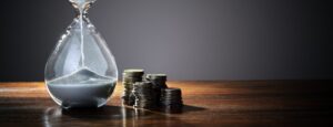 Time is money concept illustrated by a dwindling hourglass and coin currency., signifying the need for efficient time management.