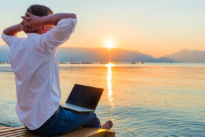 Man looks out at lake and sunset while vacationing from work.
