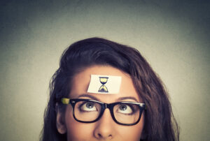 Hourglass illustration on sticky note taped to employee's forehead symbolizing the concept of time tracking for an employee's benefit.