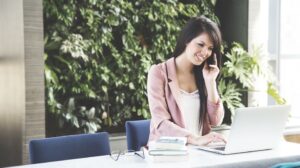 Woman on the phone working on laptop setting up rewarding activities for employees.
