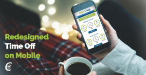 Woman sitting at home in pajamas with coffee cup looking at smartphone viewing Fingercheck's new and improved employee time off interface.