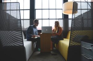 Loft startup environment, female supervisor has new male employee self-on board on laptop using paperless onboarding from Fingercheck with updated I-9 Form.