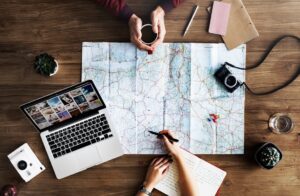 Employees in action around a map with coffee, laptop, camera, and journal, planning to make 2017 more productive than any year to date.