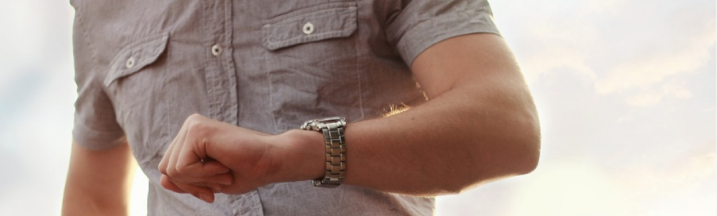 Man checks the time on his watch wondering how many ways employees cheat when clocking in.