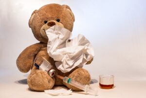 Sick teddy bear with thermometer, tissue and medicine symbolizing sick time under U.S. sick leave laws.