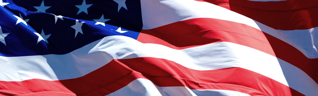 U.S. Flag blows during tax season, during which small businesses will be faced with hiring a tax preparer.