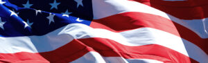 U.S. Flag blows during tax season, during which small businesses will be faced with hiring a tax preparer.