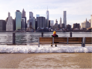 Man looks out at NYC skyline as New York bans employers from asking questions about pay history.