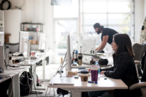 Woman seated at desk at workplace reading updates on the overtime rule on computer.