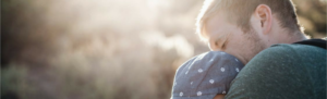 Father embracing young son in outdoor setting.