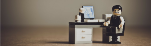 Tiny lego toy of businessman despaired by overwhelming legal issues over minor mistakes.