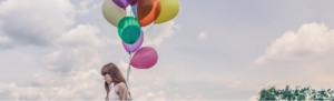 Young woman holds colorful floating balloons as symbol of floating holidays.