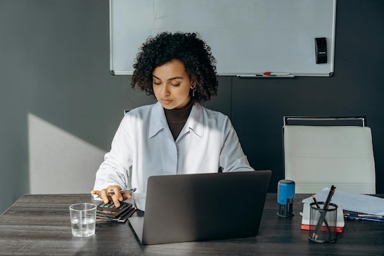 Healthcare administrator reviewing staffing schedule and labor costs on laptop