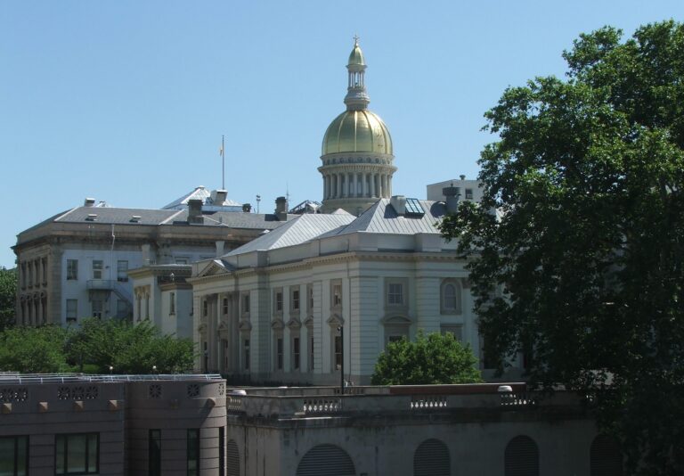 Exterior view of the New Jersey State House entrance portico in Trenton, representing state government regulations, statutory compliance, and employer labor laws.